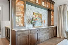 transom cabinet and marble backsplash connect the kitchen and the dining spaces