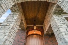 Covered porch with wood ceiling and mahogany door with curved transom