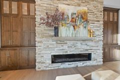 Stone linear fireplace with custom stained built-ins