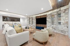 Media Room With Curved Stone Wall With Wood Accents and Bar