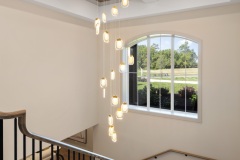 Open Staircase With Arched Window and Statement Chandelier