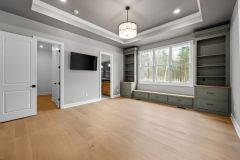 tray ceiling in primary bedroom with built-ins and window seat