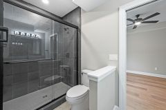 Lower Level Bathroom With Dark Tile and Glass Shower Door