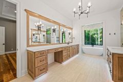 Luxury primary bathroom vanity with custom cabinetry, quartz countertops, expansive mirror, and makeup area at The Vandoren custom home in Liberty Township, Ohio.
