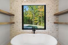 Luxury primary bathroom vanity with custom cabinetry, quartz countertops, expansive mirror, freestanding tub and makeup area at The Vandoren custom home in Liberty Township, Ohio.