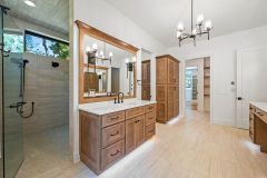Luxury primary bathroom vanity with custom cabinetry, quartz countertops, expansive mirror, freestanding tub and makeup area at The Vandoren custom home in Liberty Township, Ohio.