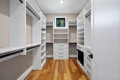 Custom walk-in closet with quartz island countertop, chandelier, built-in cabinetry, and specialty storage in The Vandoren luxury primary suite in Liberty Township, Ohio.