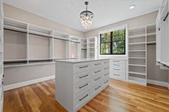 Custom walk-in closet with quartz island countertop, chandelier, built-in cabinetry, and specialty storage in The Vandoren luxury primary suite in Liberty Township, Ohio.