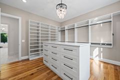 Custom walk-in closet with quartz island countertop, chandelier, built-in cabinetry, and specialty storage in The Vandoren luxury primary suite in Liberty Township, Ohio.