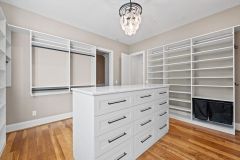 Custom walk-in closet with quartz island countertop, chandelier, built-in cabinetry, and specialty storage in The Vandoren luxury primary suite in Liberty Township, Ohio.