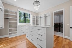 Custom walk-in closet with quartz island countertop, chandelier, built-in cabinetry, and specialty storage in The Vandoren luxury primary suite in Liberty Township, Ohio.