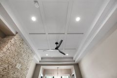 Luxury primary bedroom featuring a double tray ceiling, shallow coffered trim detail, stone fireplace and contrasting dark ceiling fan at The Vandoren custom home in Liberty Township, Ohio.