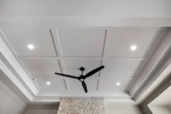 Luxury primary bedroom featuring a double tray ceiling, shallow coffered trim detail, stone fireplace and contrasting dark ceiling fan at The Vandoren custom home in Liberty Township, Ohio.