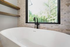 Luxury primary bathroom vanity with custom cabinetry, quartz countertops, expansive mirror, freestanding tub and makeup area at The Vandoren custom home in Liberty Township, Ohio.