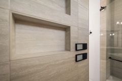 Luxury curbless walk-in shower with multiple shower heads, body sprays, built-in bench, and custom tile niches in The Vandoren primary bathroom in Liberty Township, Ohio.