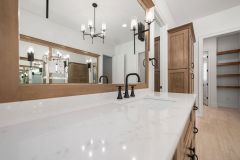 Luxury primary bathroom vanity with custom cabinetry, quartz countertops, expansive mirror, freestanding tub and makeup area at The Vandoren custom home in Liberty Township, Ohio.