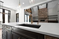 Large Kitchen Black Island With Gold Accents Open To Great Room