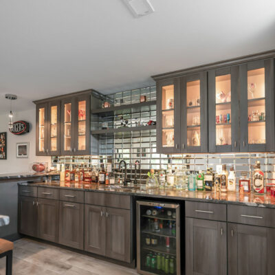 Lower Level Bar with Custom Cabinetry, Integrated Lighting and Mirror Backsplash