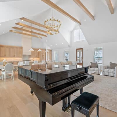 Great Room with Suspended Truss Beams, Stack Stone Fireplace and Floating Open Shelves of White Oak