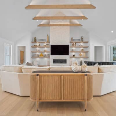 Great Room with Suspended Truss Beams, Stack Stone Fireplace and Floating Open Shelves of White Oak