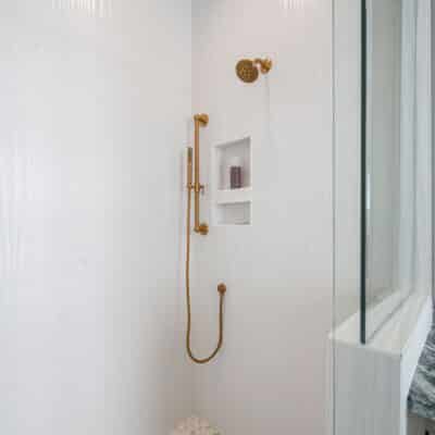 Wavy Textured Shower Ceramic Tile With Floor Pebble Tile and Gold Plumbing Fixtures