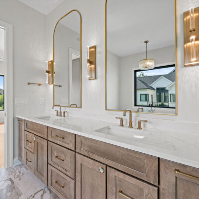 double sink vanity with built-in white oak cabinetry and brushed gold fixtures