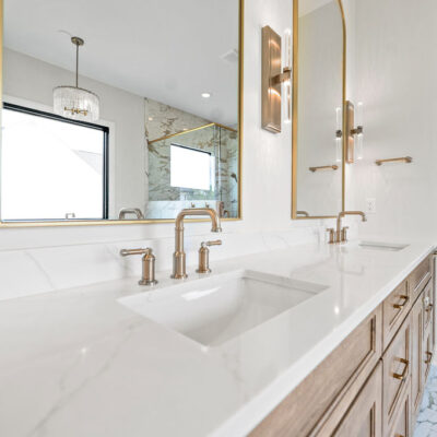 double sink vanity with built-in white oak cabinetry and brushed gold fixtures