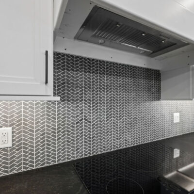 Dark kitchen tile backsplash in a herringbone pattern and light grout