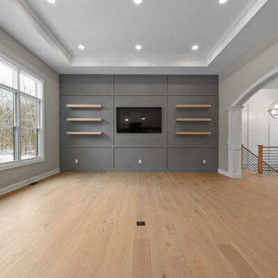 Goshen Estate Great Room with Tray Ceiling Accent Wall With Floating Modern Shelves and Open Stairway to Lower Level