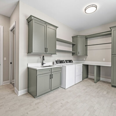 Laundry with Brick Floor and Green Custom Cabinetry