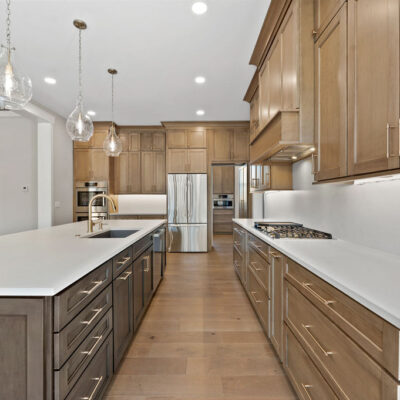 Wood Stained Kitchen Cabinetry To Ceiling With White Quartz Slab Backsplash and Black Island Cabinetry