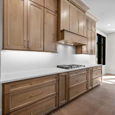 Wood Stained Kitchen Cabinetry To Ceiling With White Quartz Slab Backsplash
