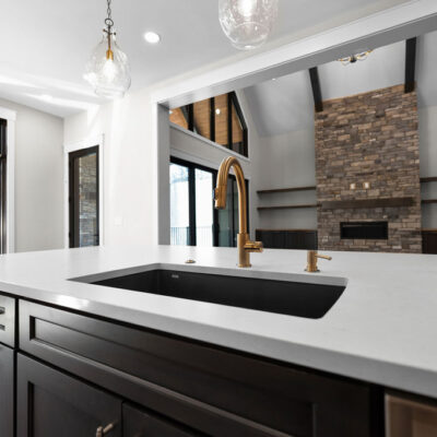 Large Kitchen Black Island With Gold Accents Open To Great Room Custom Kitchen With Stained Cabinetry, Quartz Countertops and Hidden Pantry