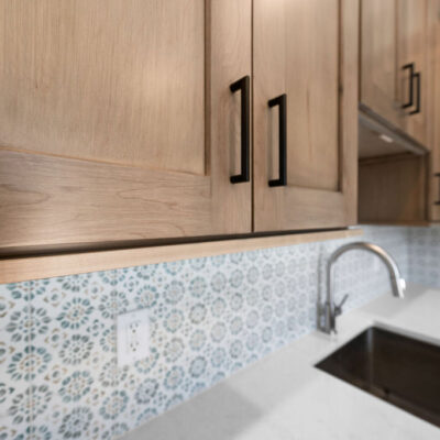 Wood Stained Cabinetry In Laundry with Graphic Tile Backsplash