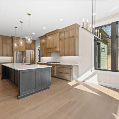 Dining Area in Custom Kitchen Wood Stained Kitchen Cabinetry To Ceiling With White Quartz Slab Backsplash and Black Island Cabinetry