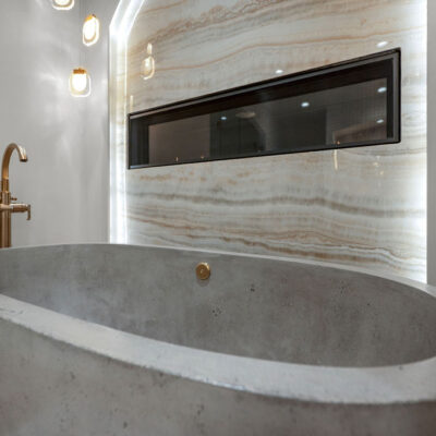 Cement Oversized Tub With Tiger Onyx Porcelain Slab Backsplash With Integrated Lighting