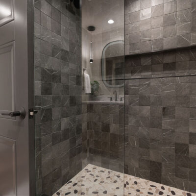 Guest Full Bathroom With Dark Tile Walls With Niche and Stone Shower Floor
