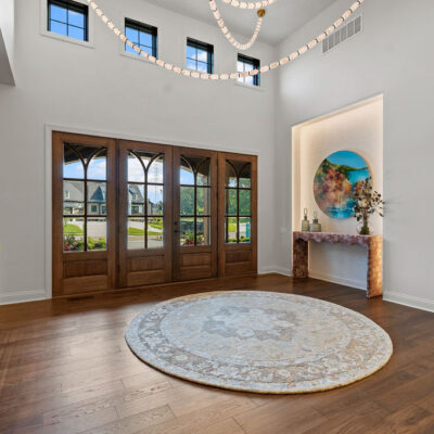 Mahogany Front Door In Entry With Statement Lighting