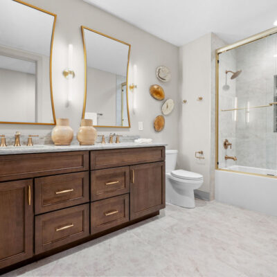 Lower level Full Bathroom With Stained Wood Custom Cabinetry and Brass Accent Hardware and Shower