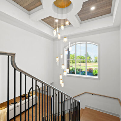 Open Staircase With Arched Window Coffered Ceiling With Circular Center With Wood Accents and Statement Chandelier