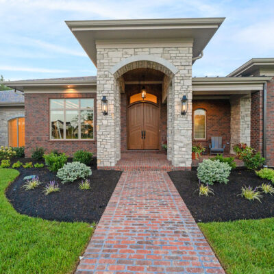 Stone Arch Covered Front Porch With Mahogany Stained Front Door With Arched Transom and Covered Front Porch
