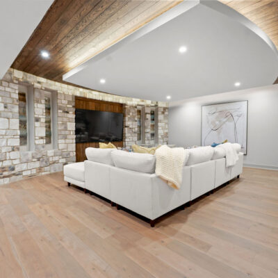 Lower Level Media Room With Inverted Tray Ceiling With Tongue and Groove Wood With Accent Lighting With Curved Stone Wall and
