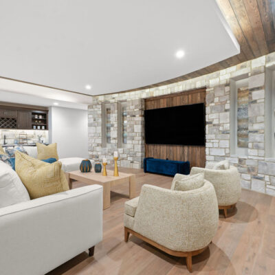 Lower Level Media Room With Inverted Tray Ceiling With Tongue and Groove Wood With Accent Lighting With Curved Stone Wall and