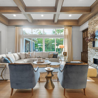 Stone Linear Fireplace In Great Room With Dark Stained Built-Ins With Wood Coffered Beam Ceiling Sliding Door With Transom Above