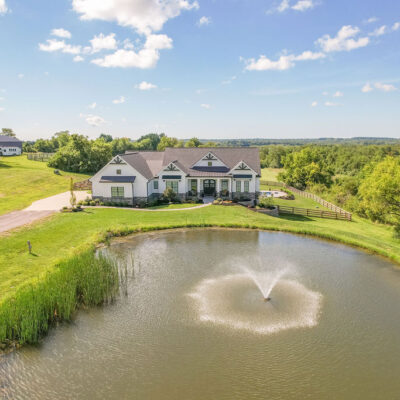 Modern Farmhouse with Gables, Siding, Stone, Metal Roof and Pond
