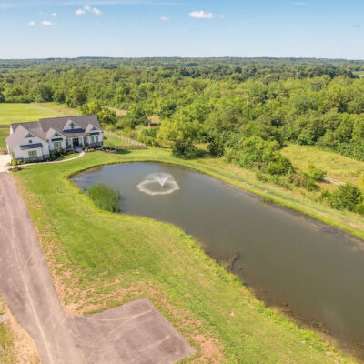 Modern Farmhouse with Gables, Siding, Stone, Metal Roof and Pond